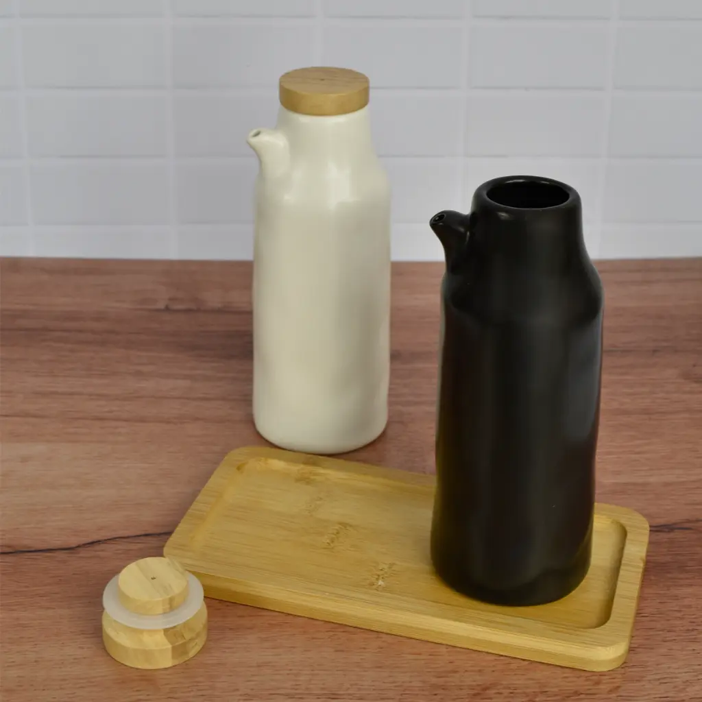 Alcuza negra sobre la base de madera y la blanca detrás, con una tapa aparte