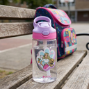 Botella Agua Niños Barbie & Pets 420ml - next to a school backpack on a wooden bench
